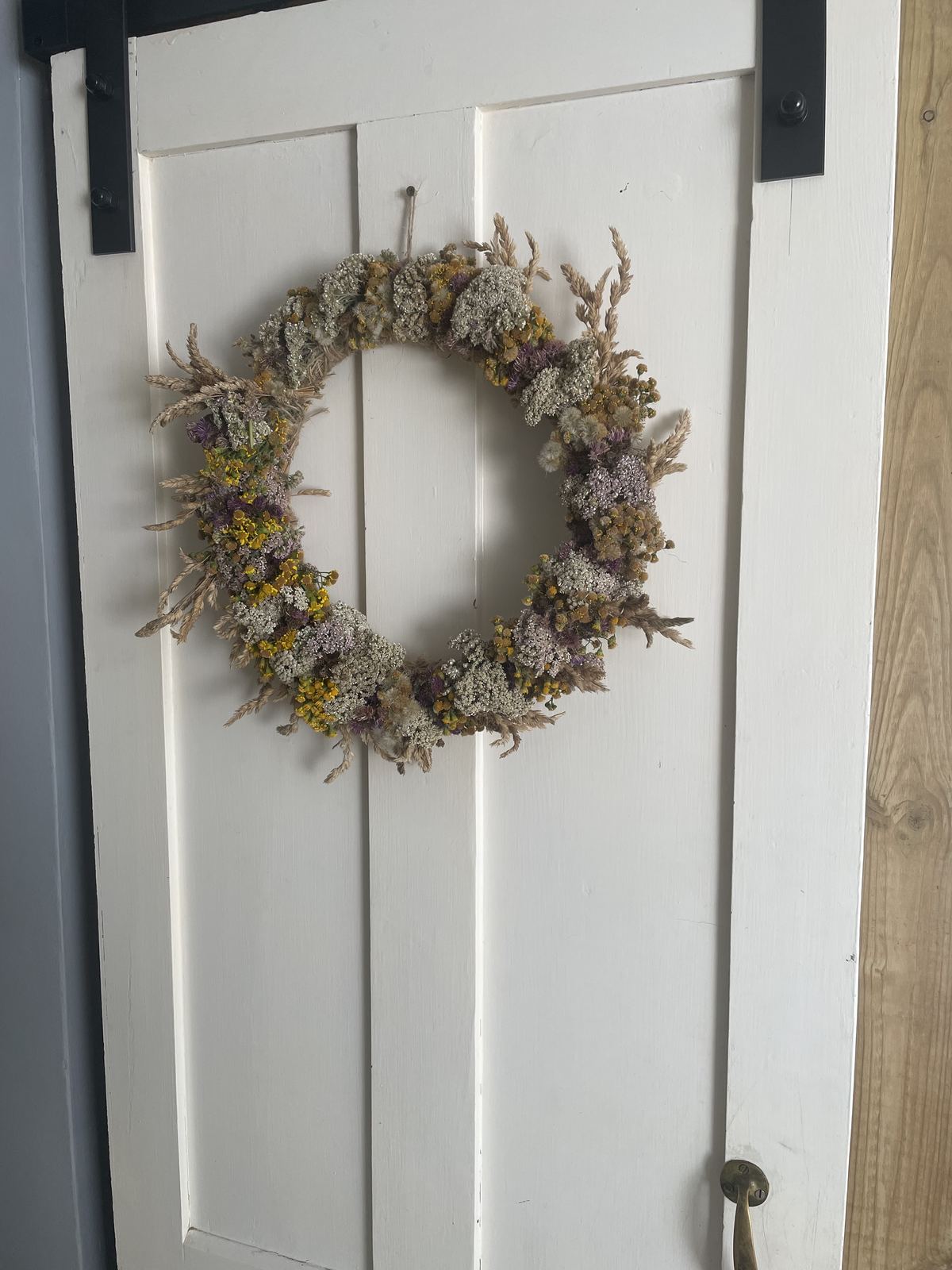 All-year door wreath hung on a white barn door